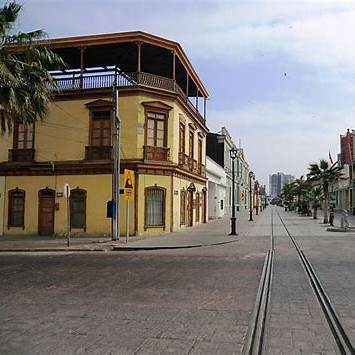 Fachadas coloridas y balcones de madera del Paseo Baquedano en Iquique, parte del patrimonio urbano salitrero y cultura local chilena.